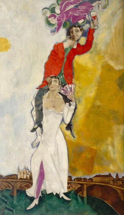 A surreal painting of a woman in a white dress standing with a man in a red jacket perched on her shoulders, holding flowers and a glass of wine. They are set against a colorful, abstract sky with a townscape and bridge in the background.