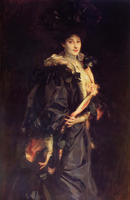 Oil portrait of a woman standing against a dark, shadowy background. She wears an elaborate black gown with voluminous sleeves, trimmed with lace and ribbons, and a large feathered black hat. Her face is softly lit, revealing a calm expression and slight smile. Pink satin ribbons and floral details accent her outfit, and her gloved hands are delicately clasped at her waist.