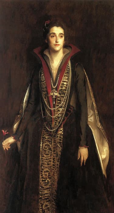 Oil portrait of a woman standing against a dark brown background, wearing an elaborate black gown with gold embroidery and long sleeves. The gown features a high, wide red collar and is adorned with layered pearl necklaces and a large jeweled cross pendant. She holds a pink flower in her left hand, and her expression is calm and composed, with her dark hair pulled back and adorned with a small red accessory.
