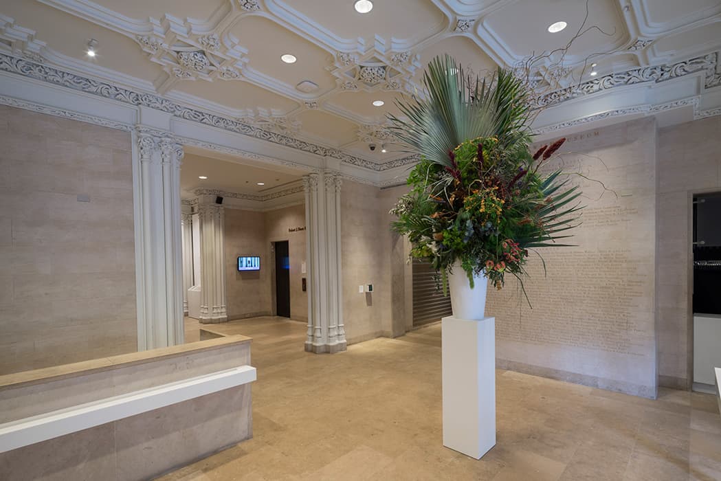 Installation view of Using Walls, Floors and Ceilings: Willem de Rooij, Bouquet XI, 2014. White fiberglass vase, plinth, flower arrangement of allergenic flowers originating from the Middle East, first version created by Bella Meyer, New York. Courtesy of Petzel Gallery, New York, and Regen Projects, Los Angeles. Photo by: David Heald