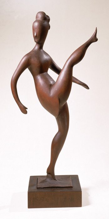 A wooden dancing figurine, leaning back, kicking one leg up gracefully. The forms are smooth and rounded.